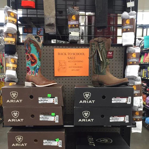 A display of Ariat cowboy boots on boxes, surrounded by Carhartt socks. A 