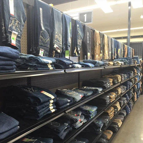 Shelves filled with neatly folded jeans sorted by color and style in a store. A variety of denim shades creates an organized, inviting display.